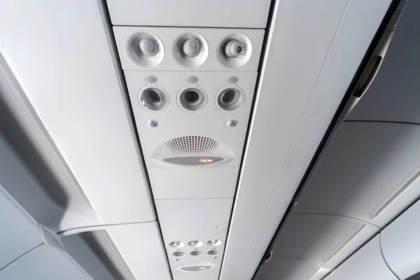 Airplane air conditioning control panel over seats. Stuffy air in aircraft cabin with people. New low-cost airline.