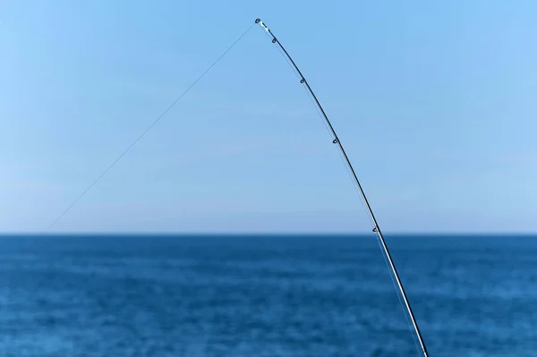 Vara de pesca contra o oceano azul ou fundo do mar, espaço de cópia. À espera do maior transporte. Meditativo relaxar esporte . — Fotografia de Stock