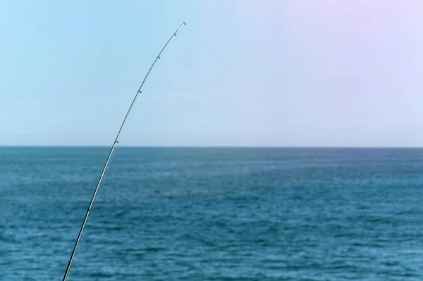 Vara de pesca contra o oceano azul ou fundo do mar, espaço de cópia. À espera do maior transporte. Meditativo relaxar esporte . — Fotografia de Stock