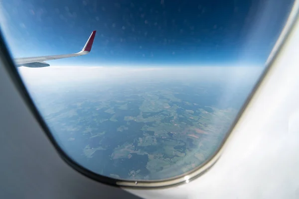 Okno s letadlem má výhled na zatažené nebe a zemi. Nádherná krajina z kabiny letadel. Létání bez strachu z létání, incidentů a turbulencí. — Stock fotografie