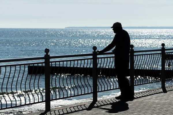 Hombre envejecido sueña con aventuras de la vida, más allá de viajar y mira al mar. Vista trasera trasera, espacio para copiar. El viejo viudo de cáncer echa de menos a su esposa. Clima soleado y mar azul limpio . —  Fotos de Stock