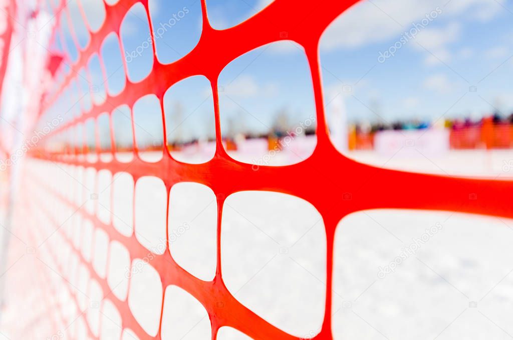 Safety outdoor slope track fence, winter background. Fence to protect spectators at sports events, or to indicate course at extreme sports - dog sledding, snowboarding or skiing