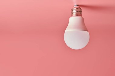 Ampul, kopyalama alanı. Enerji tasarrufu minimal fikir kavramı. Pembe arka plan.