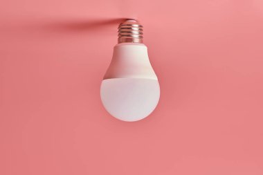 Ampul, kopyalama alanı. Enerji tasarrufu minimal fikir kavramı. Pembe arka plan.
