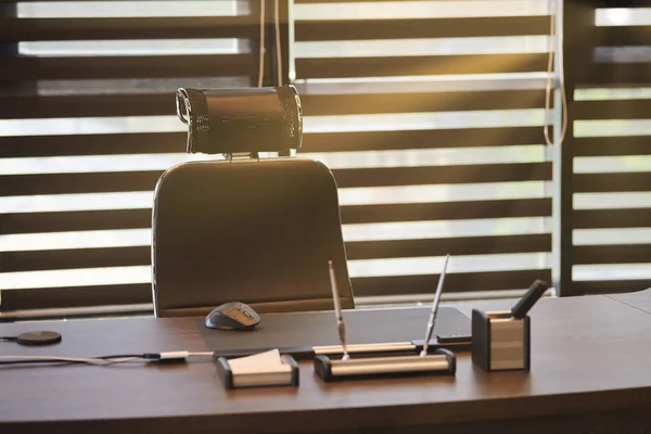 Büroarbeitsplatz. Sonnenlicht am Arbeitsplatz für Chef, Chef oder andere Mitarbeiter. Tisch und bequemer Stuhl. Licht durch die halb offenen Jalousien — Stockfoto