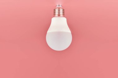Enerji tasarrufu ampulü, kopyalama alanı, pembe zemin. Asgari fikir kavramı.