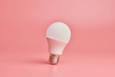 Ampul, kopyalama alanı. Enerji tasarrufu minimal fikir kavramı. Pembe arka plan.