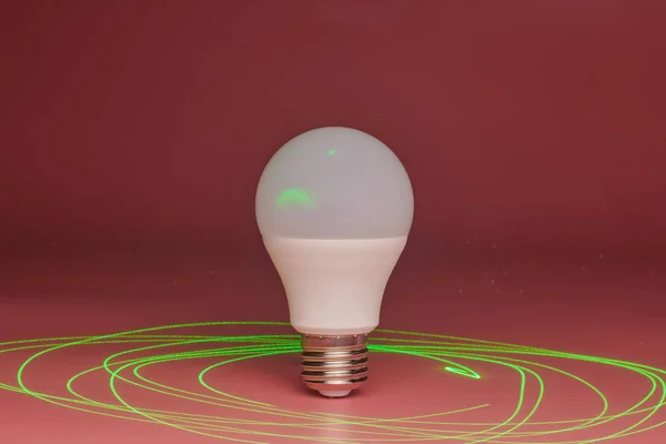 Energy saving light bulb, green laser beam around, copy space. Minimal idea concept.