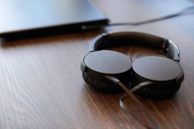 Kulaklıklar ofis masasında. Laptop 'a bağlı kulaklıklar, kopyalama alanı. İşte müzik dinlemek.