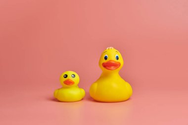 İki sarı plastik ördek oyuncağı, kopyalama alanı. Sevimli komik banyo oyuncakları, asgari kidult konsepti. Pembe arkaplan.