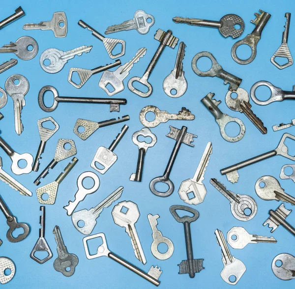 Τα κλειδιά είναι σε μπλε φόντο. Κλειδιά κλειδαριάς πόρτας και χρηματοκιβώτια για ασφάλεια ακινήτων και προστασία σπιτιού. Διαφορετικοί αντίκες και νέοι τύποι κλειδιών. — Φωτογραφία Αρχείου
