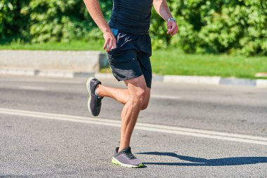 Koşan adam. Şehir yolunda spor kıyafetleriyle koşan atletik bir adam. Sağlıklı yaşam tarzı, spor hobisi. Sokak çalışması, açık hava koşusu.