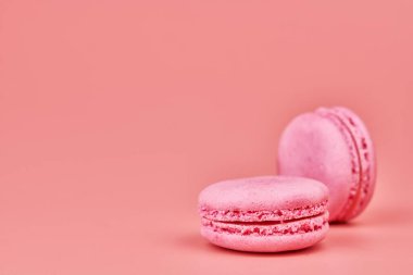 Pembe arka planda makarnalar. Badem ve hindistan cevizinden renkli küçük kurabiyeler. Popüler şekerlemeler. Atıştırmalık lezzetli yemekler, kopyalama alanı