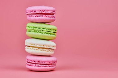 Pembe arka planda makarnalar. Badem ve hindistan cevizinden renkli küçük kurabiyeler. Popüler şekerlemeler. Atıştırmalık lezzetli yemekler, kopyalama alanı