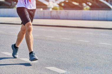 Koşan adam. Şehir yolunda spor kıyafetleriyle koşan atletik bir adam. Sağlıklı yaşam tarzı, spor hobisi. Sokak çalışması, açık hava koşusu.