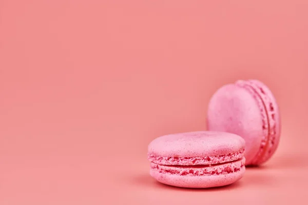 Macaroons on pink background. Colorful small cookie from ground almonds and coconut. Popular confectionery. Tasty snack food for take away, copy space