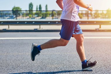 Koşan adam. Şehir yolunda spor kıyafetleriyle koşan atletik bir adam. Sağlıklı yaşam tarzı, spor hobisi. Sokak çalışması, açık hava koşusu.