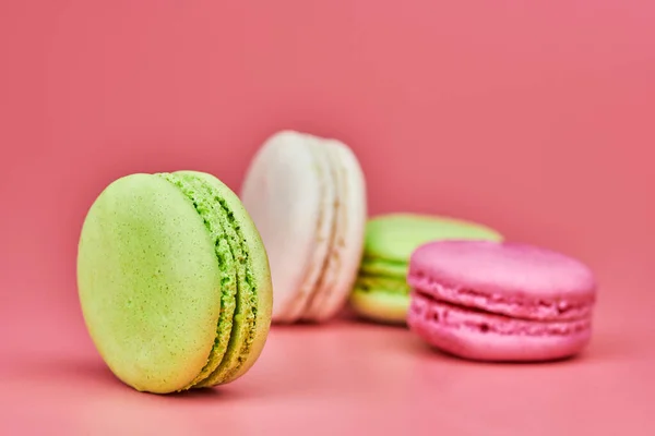 Macaroons on pink background. Colorful small cookie from ground almonds and coconut. Popular confectionery. Tasty snack food for take away, copy space