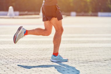 Koşan adam. Şehir yolunda spor kıyafetleriyle koşan atletik bir adam. Sağlıklı yaşam tarzı, spor hobisi. Sokak çalışması, açık hava koşusu.