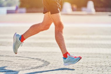 Koşan adam. Şehir yolunda spor kıyafetleriyle koşan atletik bir adam. Sağlıklı yaşam tarzı, spor hobisi. Sokak çalışması, açık hava koşusu.