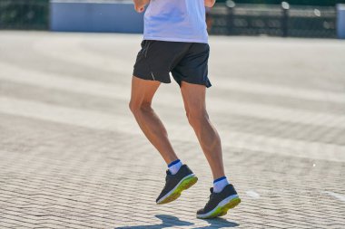Koşan adam. Şehir yolunda spor kıyafetleriyle koşan atletik bir adam. Sağlıklı yaşam tarzı, spor hobisi. Sokak çalışması, açık hava koşusu.