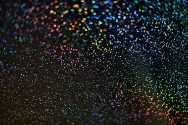 Gökkuşağı pırıltısı. Soyut zemin. Renkli parlayan gökkuşağı damlaları ve siyah arka planda ışıklar. Bulanık pulların ve bokeh 'in şenlikli parlak parıltısı..