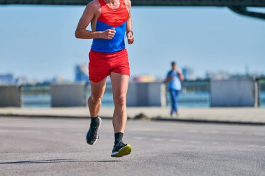 Koşan adam. Şehir yolunda spor kıyafetleriyle koşan atletik bir adam. Sağlıklı yaşam tarzı, spor hobisi. Sokak çalışması, açık hava koşusu.