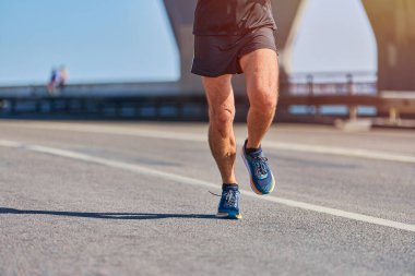 Koşan adam. Şehir yolunda spor kıyafetleriyle koşan atletik bir adam. Sağlıklı yaşam tarzı, spor hobisi. Sokak çalışması, açık hava koşusu.