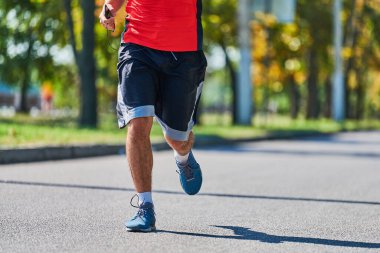 Koşan adam. Şehir yolunda spor kıyafetleriyle koşan atletik bir adam. Sağlıklı yaşam tarzı, spor hobisi. Sokak çalışması, açık hava koşusu.