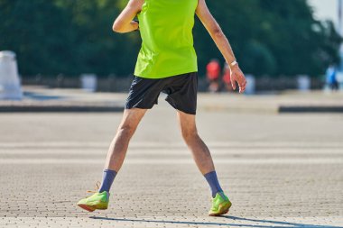 Koşan adam. Şehir yolunda spor kıyafetleriyle koşan atletik bir adam. Sağlıklı yaşam tarzı, spor hobisi. Sokak çalışması, açık hava koşusu.
