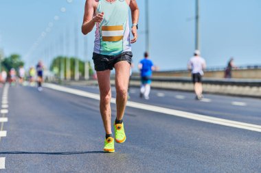 Koşan adam. Şehir yolunda spor kıyafetleriyle koşan atletik bir adam. Sağlıklı yaşam tarzı, spor hobisi. Sokak maratonu, açık hava koşusu.