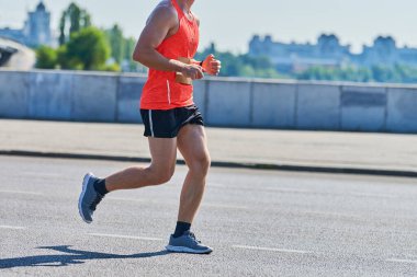 Koşan adam. Şehir yolunda spor kıyafetleriyle koşan atletik bir adam. Sağlıklı yaşam tarzı, spor hobisi. Sokak çalışması, açık hava koşusu.