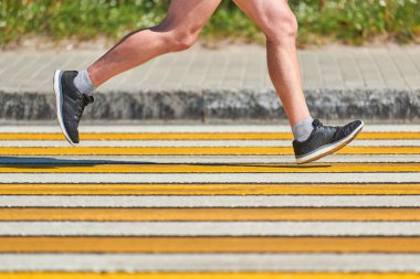 Yaya geçidinde koşan adam, kopyalama alanı. Şehir yolunda spor kıyafetleriyle koşan atletik bir adam. Sağlıklı yaşam tarzı, spor hobisi. Trafik ihlali. Sokak çalışması, açık hava koşusu.