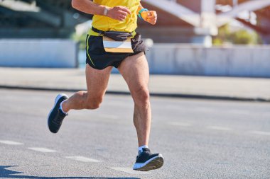 Koşan adam. Şehir yolunda spor kıyafetleriyle koşan atletik bir adam. Sağlıklı yaşam tarzı, spor hobisi. Sokak çalışması, açık hava koşusu.
