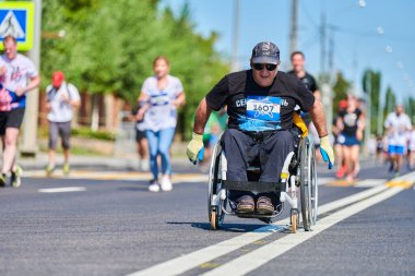 Voronezh, Rusya - 24.08.2019 - koşucular arasında tekerlekli sandalyedeki engelli adam. Şehir yolunda geçersiz. Koşucular maratonu ve şampiyonluk yarışması. Sokak dışarı koşuyor. Sağlıklı spor etkinliği.