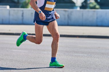 Koşan adam. Şehir yolunda spor kıyafetleriyle koşan atletik bir adam. Sağlıklı yaşam tarzı, spor hobisi. Sokak çalışması, açık hava koşusu.