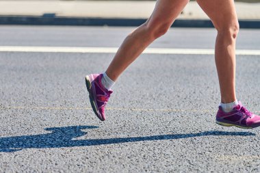 Koşan kadın. Spor kıyafetleriyle şehir yolunda koşan bir kadın. Sağlıklı yaşam tarzı, spor hobisi. Sokak çalışması, açık hava koşusu.