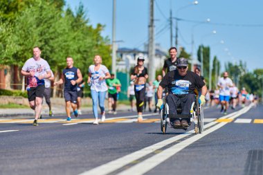 Voronezh, Rusya - 24.08.2019 - koşucular arasında tekerlekli sandalyedeki engelli adam. Şehir yolunda geçersiz. Koşucular maratonu ve şampiyonluk yarışması. Sokak dışarı koşuyor. Sağlıklı spor etkinliği.