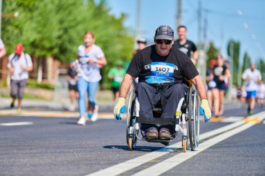 Voronezh, Rusya - 24.08.2019 - koşucular arasında tekerlekli sandalyedeki engelli adam. Şehir yolunda geçersiz. Koşucular maratonu ve şampiyonluk yarışması. Sokak dışarı koşuyor. Sağlıklı spor etkinliği.