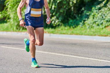 Koşan yaşlı adam. Şehir yolunda spor kıyafetleriyle koşan yaşlı bir adam. Sağlıklı yaşam tarzı, spor hobisi. Sokak çalışması, açık hava koşusu.