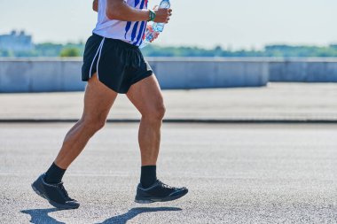 Koşan adam. Şehir yolunda spor kıyafetleriyle koşan atletik bir adam. Sağlıklı yaşam tarzı, spor hobisi. Sokak çalışması, açık hava koşusu.