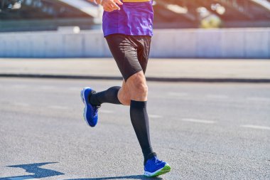 Koşan adam. Şehir yolunda spor kıyafetleriyle koşan atletik bir adam. Sağlıklı yaşam tarzı, spor hobisi. Sokak çalışması, açık hava koşusu.