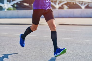 Koşan adam. Şehir yolunda spor kıyafetleriyle koşan atletik bir adam. Sağlıklı yaşam tarzı, spor hobisi. Sokak çalışması, açık hava koşusu.