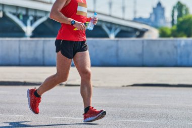 Koşan adam. Şehir yolunda spor kıyafetleriyle koşan atletik bir adam. Sağlıklı yaşam tarzı, spor hobisi. Sokak çalışması, açık hava koşusu.