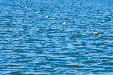 Deniz suyunda yüzen şamandıralar. Yüzen insanlar, yatlar ve diğer gemiler için güvenli beyaz fenerler. Boşluğu kopyala.