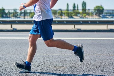 Koşan adam. Şehir yolunda spor kıyafetleriyle koşan atletik bir adam. Sağlıklı yaşam tarzı, spor hobisi. Sokak çalışması, açık hava koşusu.