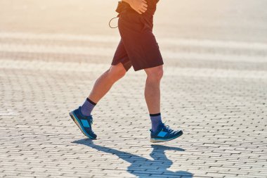 Koşan adam. Şehir yolunda spor kıyafetleriyle koşan atletik bir adam. Sağlıklı yaşam tarzı, spor hobisi. Sokak çalışması, açık hava koşusu.