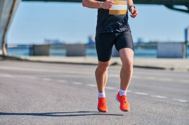 Koşan adam. Şehir yolunda spor kıyafetleriyle koşan atletik bir adam. Sağlıklı yaşam tarzı, spor hobisi. Sokak çalışması, açık hava koşusu.