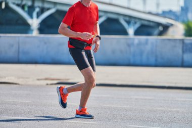 Koşan adam. Şehir yolunda spor kıyafetleriyle koşan atletik bir adam. Sağlıklı yaşam tarzı, spor hobisi. Sokak çalışması, açık hava koşusu.