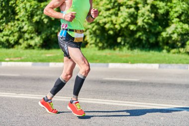 Koşan adam. Şehir yolunda spor kıyafetleriyle koşan atletik bir adam. Sağlıklı yaşam tarzı, spor hobisi. Sokak çalışması, açık hava koşusu.